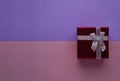 Red gift box with silver bow on two-tone pink and blue paper background top view with copy space. Can be used for Valentines day Royalty Free Stock Photo