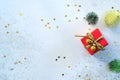 Red gift box with small decorated Christmas tree and golden star flakes on white cement background. MERRY CHRISTMAS and HAPPY NEW Royalty Free Stock Photo
