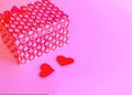 Red gift box tied with a red ribbon on a pink trendy background.