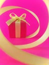 Red gift box at the end of the spiral yellow ribbon, fuchsia background, vertical. Royalty Free Stock Photo