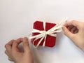 Red gift box with white bow on white background and hands holding ribbons Royalty Free Stock Photo