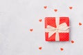 Red gift box with white ribbon bow on white background with red heart confetti. Christmas present, valentine day