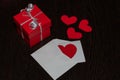 A red gift box with a white ribbon and bow, and an envelope full of hearts. Royalty Free Stock Photo