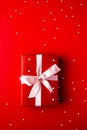 Red gift box with white ribbon and bow on red background. Generative AI Royalty Free Stock Photo