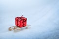 Red gift box on wooden sled in winter in snow, christmas gifts delivery background Royalty Free Stock Photo