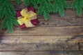 Red gift box with yellow bow on wooden background with Christmas tree branches. New Year Royalty Free Stock Photo