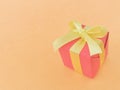 Red gift box with yellow ribbon on orange background. copy space. Royalty Free Stock Photo