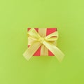 Red gift box with yellow ribbon on light green background. Square. Royalty Free Stock Photo