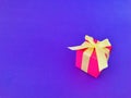 Red gift box with yellow ribbon on purple background . copy space. Royalty Free Stock Photo