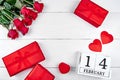 Red gift boxes with ribbon bow, two hearts, bouquet of red roses and wooden block calendar on white background. Royalty Free Stock Photo