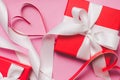 Red gift boxes tied with a white ribbon, two paper hearts on a pink background Royalty Free Stock Photo