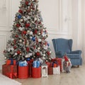 Red gift boxes under Christmas tree and blue armchair behind Royalty Free Stock Photo