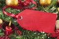 Red gift tag hanging on a christmas tree with decorations, copy space