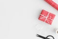 Red gift, twine, scissors and paper roll on a white table. Flat lay with blank copy space Royalty Free Stock Photo
