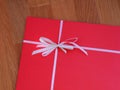 A red gift with white bow on a wooden background