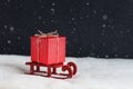 Red gift on the wooden sledge on snow