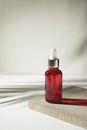 Red glass bottle with dropper pipette with serum or essential oil on concrete plate for product presentation. Royalty Free Stock Photo