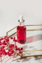 Red glass bottle with dropper pipette with serum or essential oil on glass plate for product presentation. Royalty Free Stock Photo