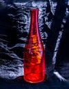 A red glass bottle and surface reflections on a black background Royalty Free Stock Photo