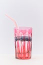 Red glass filled with vodka and fresh blueberrie fruits with drinking straw