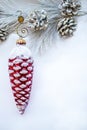 Red glass retro pine cone with snow Christmas ornament hanging from flocked branch against white background - Room for copy Royalty Free Stock Photo