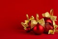 Red glossy different christmas balls heap with gold shimmer bow on bright red background, copy space. Christmas background.