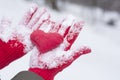 Red gloves covered with snow holding a heart Royalty Free Stock Photo
