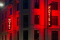 Red glowing neon sign HOTEL. Red light shining on walls.