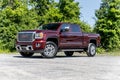 Red GMC pickup truck parked in a lush green grassy field.