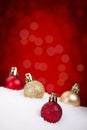 Red and gold Christmas baubles on snow, red background