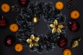 Red and gold Christmas tree decor and tangerines on black background. Winter Holiday season top view composition Royalty Free Stock Photo