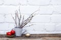 Red and gold Easter eggs and decorative ceramic grey watering can with willow on wooden and white brick wall background. Copy