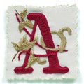 A red and gold embroidered letter a with leaves, embroidery on white background