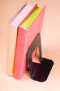 Red and golden books leaning on bookend