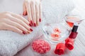 Red and golden manicure with spa essentials on white wooden table.