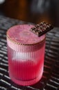 Red grapefruit cocktail with foam, ice and a piece of chocolate on a black table in restaurant Royalty Free Stock Photo