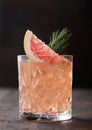 Red grapefruit summer juice cocktail in glass with rosemary and fruit slice on black background Royalty Free Stock Photo