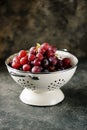 Red grapes in a white colander on a gray background. Royalty Free Stock Photo