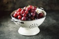 Red grapes in a white colander on a gray background. Royalty Free Stock Photo