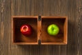 Red and green apple are separated in a wooden box. The concept of difference and dissimilarity, skin color.