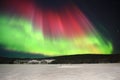 Red and green aurora above frozen lake in northern Sweden