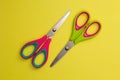 Red and green baby scissors isolated on a yellow background Royalty Free Stock Photo