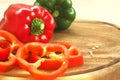 Red and green bell peppers on wooden cutting board with copy space