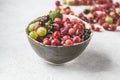 Red, green and black gooseberries in a bowl on gray background Royalty Free Stock Photo