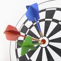 Red, green and blue darts sticking in dart board