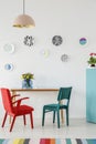 Red and green chair, plates as wall decoration, lamp, table with