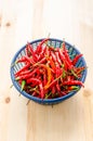 Red and green chili in blue plastic basket on wooden background. Royalty Free Stock Photo