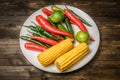Red and green chili pepper, corn on plate on wooden background Royalty Free Stock Photo