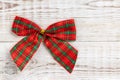 Red and green Christmas checkered bow, holiday winter concept of new year on white wooden background, flat lay, top view, copy Royalty Free Stock Photo