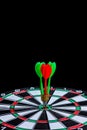 Red and green dart arrow hitting target center is Dart board Isolated on black background Royalty Free Stock Photo